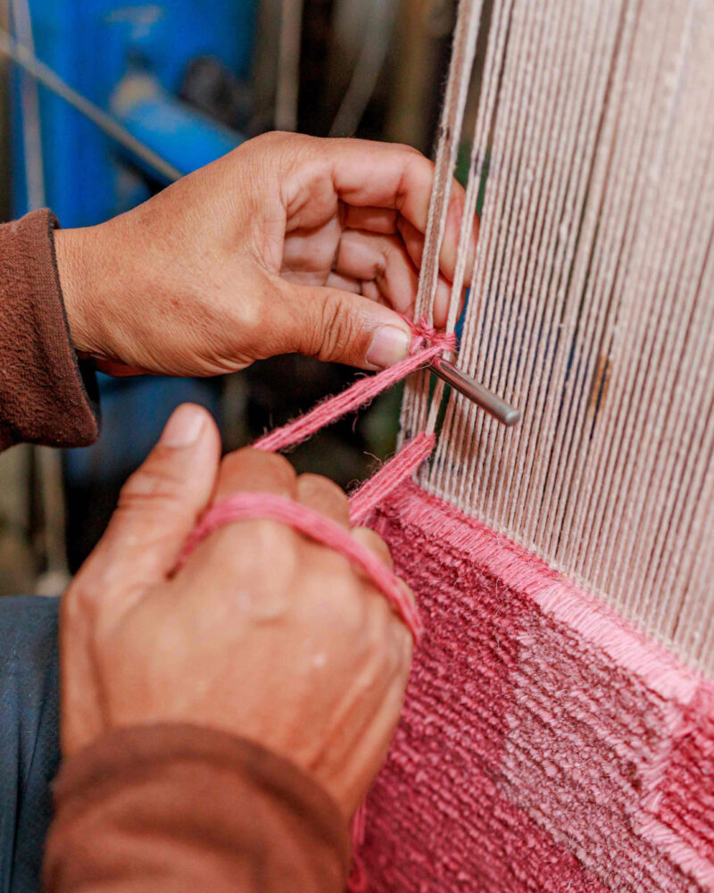 Woven with precision, wool yarn is knotted around a cotton warp, line by line.